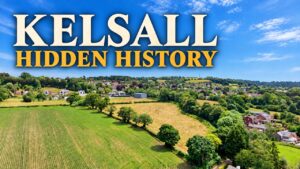 Drone view across fields towards Kelsall village, with the words Kelsall Hidden History.